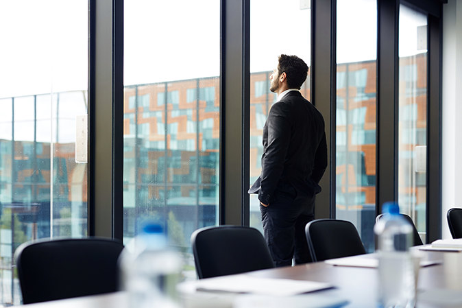 Young, professional man looking out a conference room window