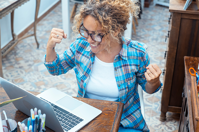Female student triumphantly sitting at laptop