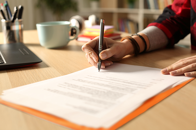 Person signing document on desk