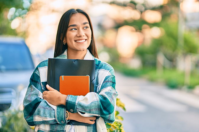 Young woman smiling holding books