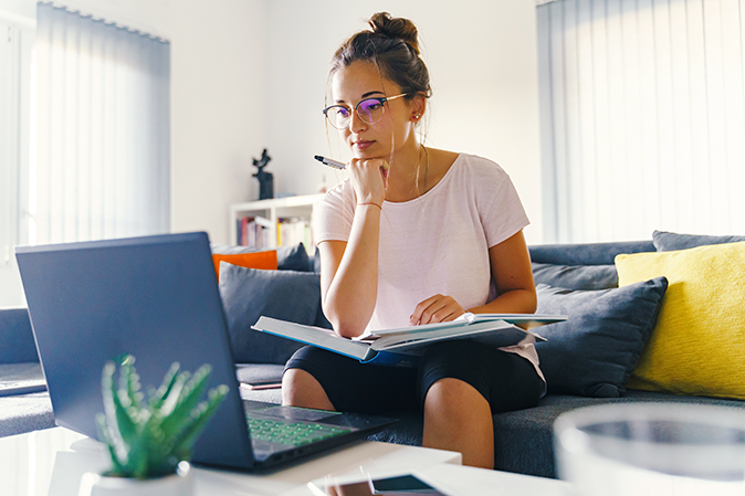 Young woman studying intently online in her living room.