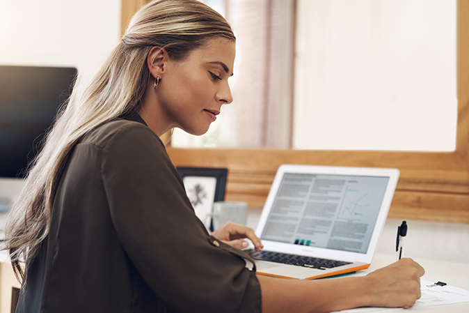 Young woman writing a legal document with a laptop in front of her