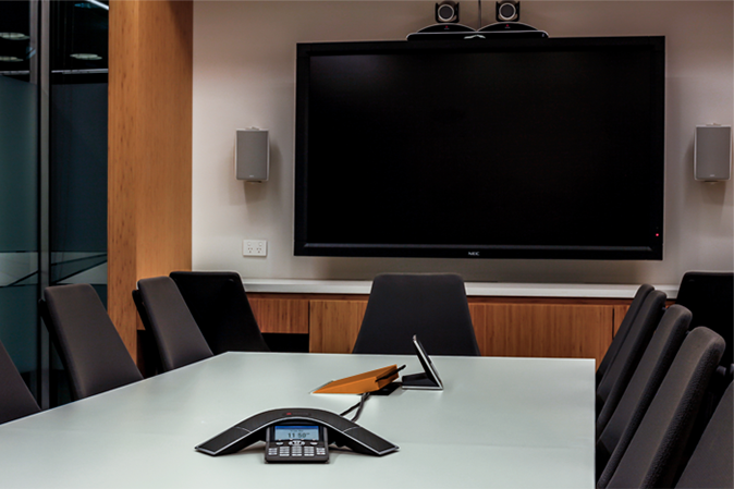 Modern conference room with communication equipment on the desk and a tv on the wall