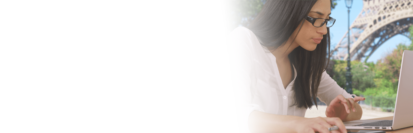 Young woman typing on a laptop outside with the Eiffel Tower in the background
