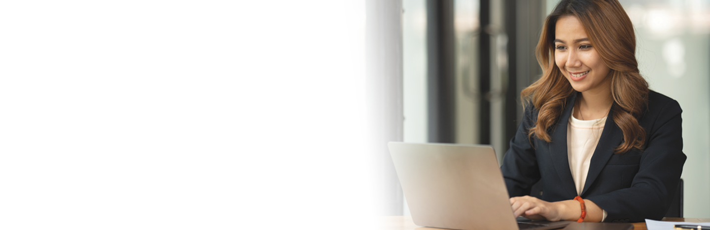 Young woman smiling while working on laptop at her desk